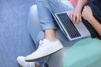 Close up of team member working with laptop on their lap