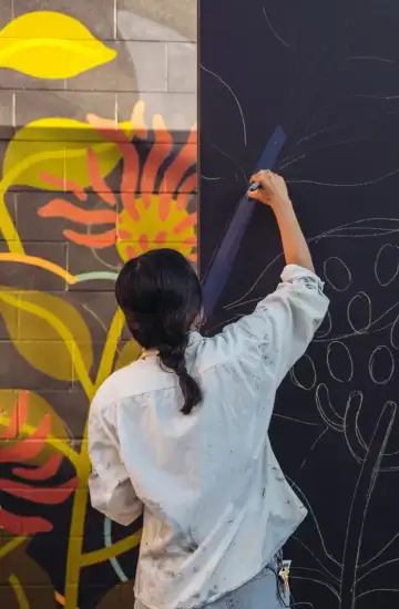 Artist sketching mural outlines, symbolizing creativity and tailored marketing work.
