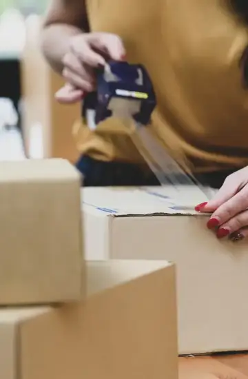 erson taping cardboard box, symbolizing ecommerce fulfillment due to increased sales from digital marketing efforts.
