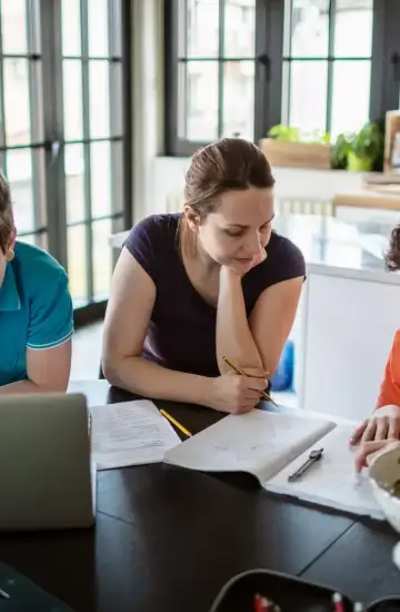 Parent helping children with homework at the kitchen table, representing education tech growth through digital marketing.