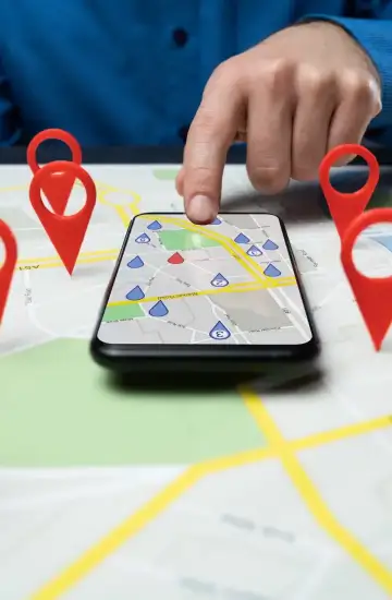 Person using smartphone on a map with location pins, symbolizing local SEO strategy.