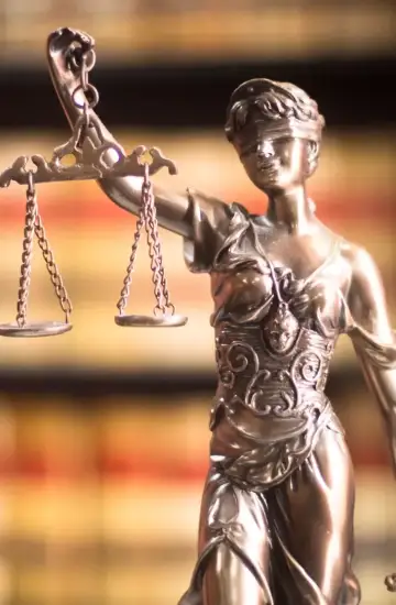 Statue of Lady Justice holding balanced scales in front of law books, symbolizing modern digital marketing for law firms.