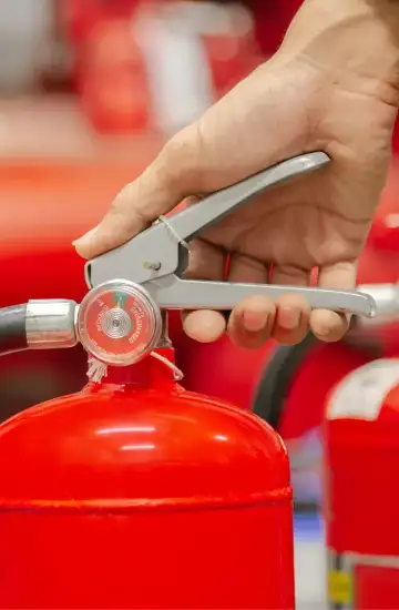 Person’s hand gripping the handle of a red fire extinguisher, symbolizing growth through digital marketing.