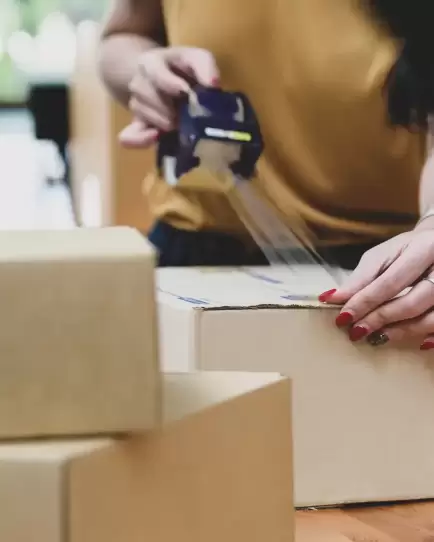 erson taping cardboard box, symbolizing ecommerce fulfillment due to increased sales from digital marketing efforts.
