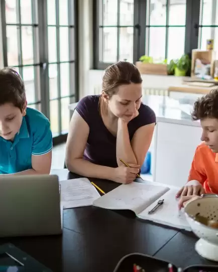 Parent helping children with homework at the kitchen table, representing education tech growth through digital marketing.