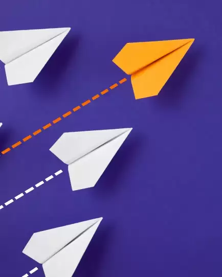 Orange paper plane flying ahead of white ones on a purple background, representing brand differentiation through SEO.