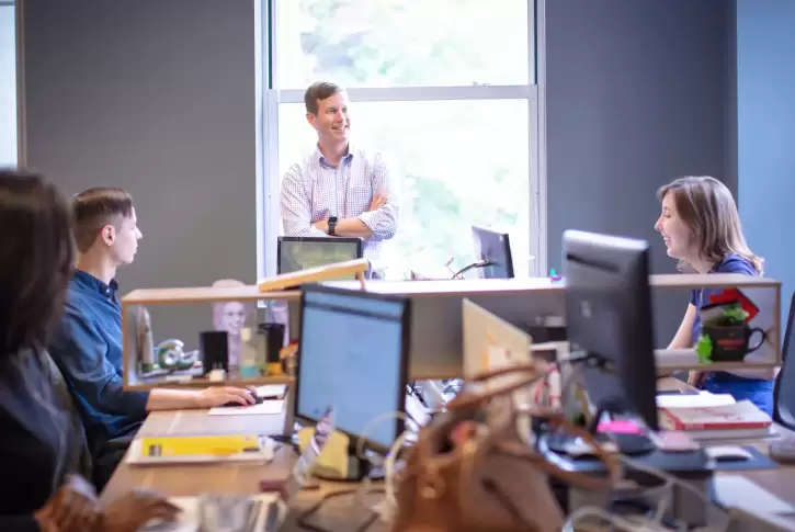 Several coworkers conversing at a shared desk space
