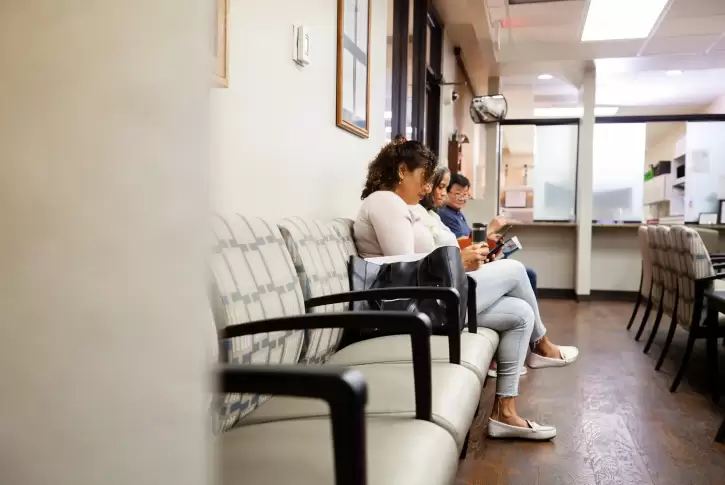 Image depicting people waiting in a doctor's office waiting room.