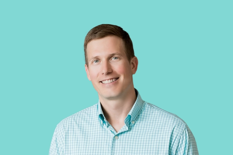 Portrait of Andrew Miller on a teal background.